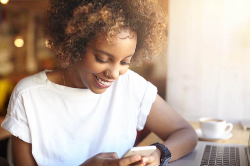 Pontuação de score | Foto de uma mulher sorrindo para o celular | Como limpar o seu nome | Eu Dou Conta