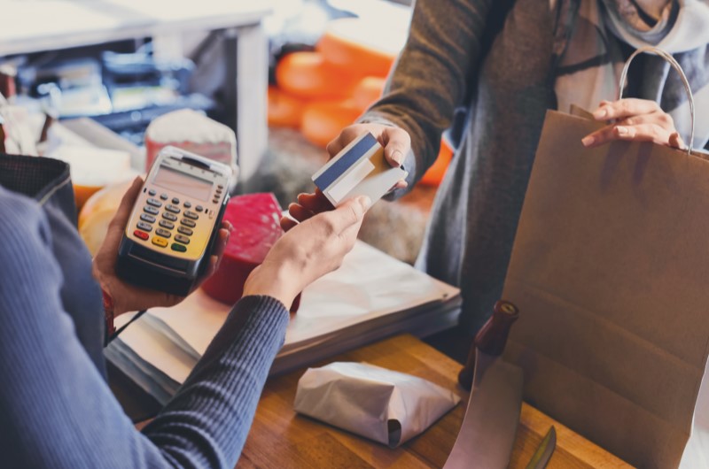 Crédito ou débito: quando usar cada um | Foto de uma pessoa fazendo compras em uma loja | Como limpar o seu nome