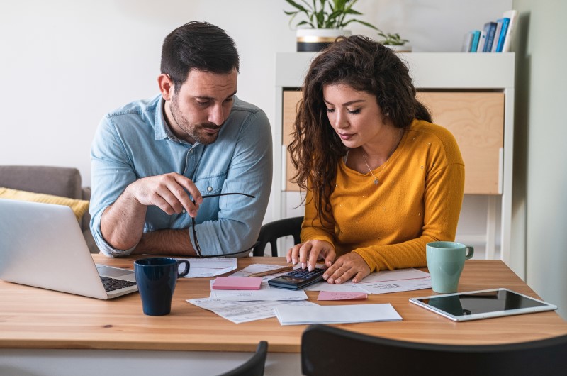 Um homem e uma mulher pagando contas | Como pagar dívidas negativadas | Dúvidas sobre dívidas | Eu Dou Conta