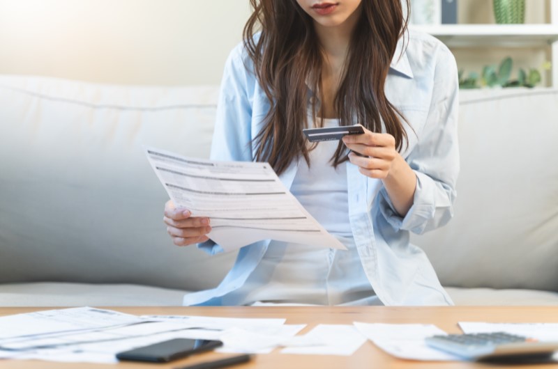 Mulher olhando para as dívidas de cartão de crédito | O que é negativado | Como limpar o seu nome | Eu Dou Conta