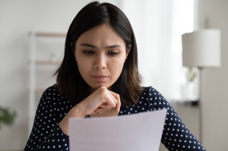 Mulher jovem olhando preocupada para uma dívida | Pontuação de score | Eu Dou Conta