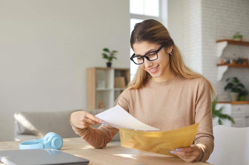 Como consultar o CNJP de uma empresa | Mulher sorrindo olhando para papéis | Como limpar o seu nome | Eu Dou Conta