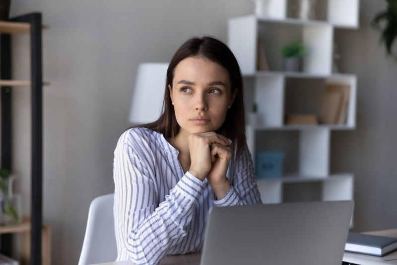 Quais são os tipos de renegociação de dívidas | Foto de uma mulher pensando na frente do computador | Dúvidas sobre dívidas | Eu Dou Conta