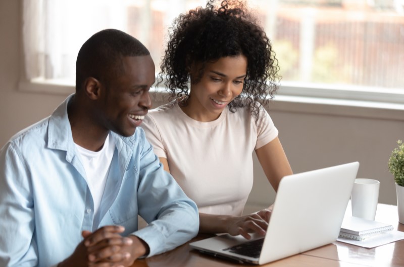 Dicas para manter o nome limpo | Um homem e uma mulher sorrindo e pesquisando na internet | Eu Dou Conta