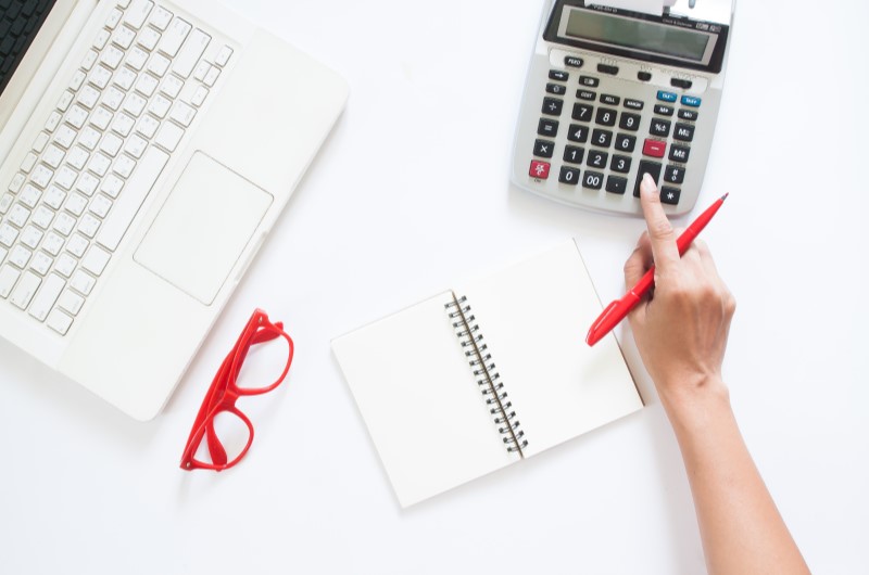 Como calcular o décimo terceiro salário | Foto de uma mão feminina fazendo contas | Economia e renda extra | Eu Dou Conta