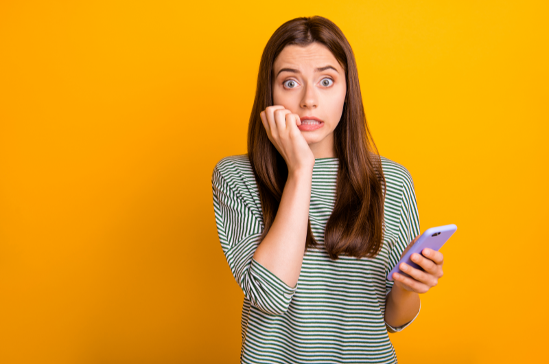 Erros do planejamento financeiro | Foto de uma menina preocupada segurando o celular | Como limpar o seu nome | Eu Dou Conta