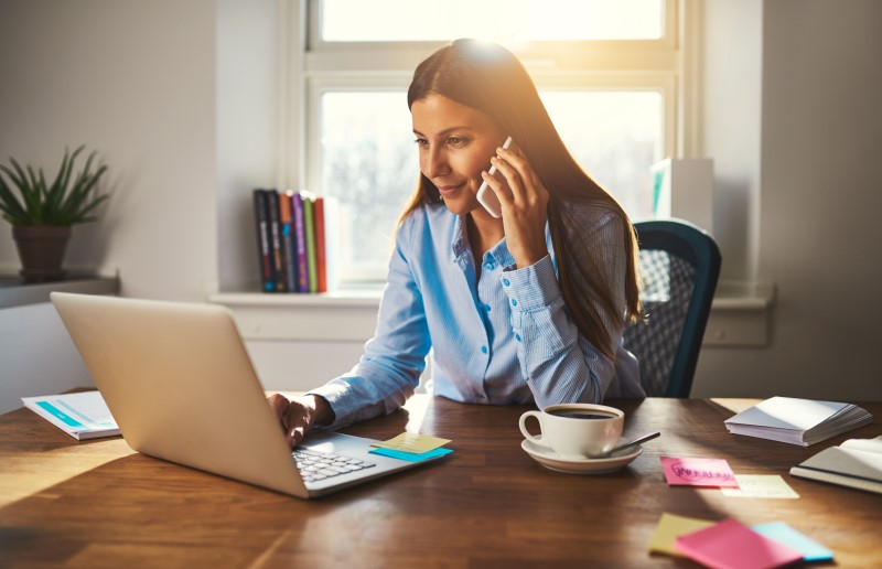 Quais são as estratégias de negociação | Foto de uma mulher pesquisando no computador e falando no telefone | Dúvidas sobre dívidas | Eu Dou Conta