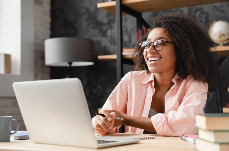 O que é o Desenrola Brasil | Foto de uma mulher sorridente usando o notebook | Como limpar o seu nome | Blog Eu Dou Conta 