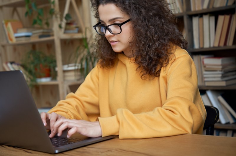 Como juntar dinheiro ganhando pouco? | Foto de uma mulher focada usando o notebook | Economia e renda extra | Blog Eu Dou Conta