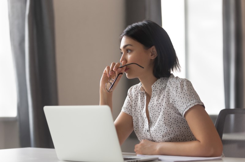 Como saber se o nome está sujo | Foto de uma mulher em frente ao notebook, com uma expressão pensativa | Como limpar o seu nome | Eu Dou Conta