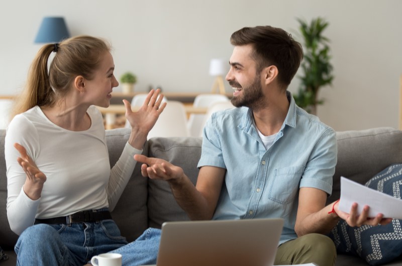 Dicas para fazer um bom financiamento | Foto de um casal sentado no sofá com uma expressão feliz | Dúvidas sobre dívidas | Eu Dou Conta 