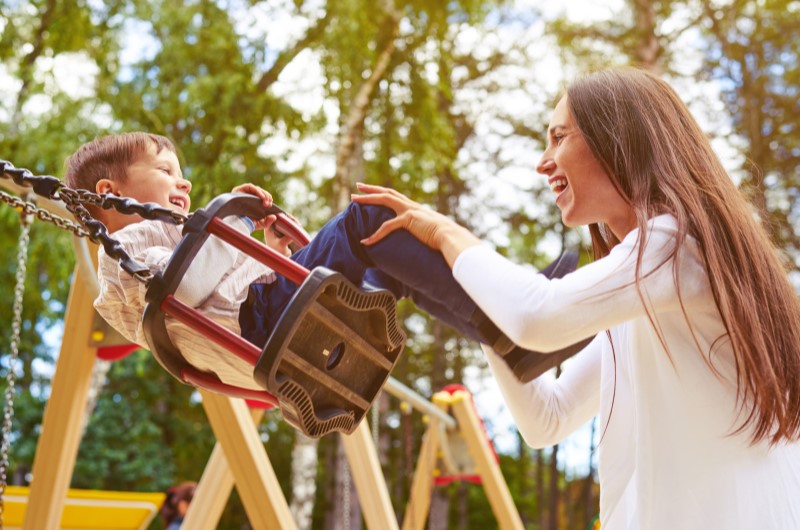 Qual é a origem do Dia das Crianças | Foto de uma mãe brincando com seu filho em um balanço | Economia e renda extra | Eu Dou Conta