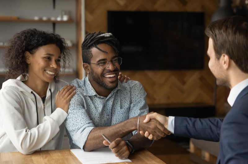 Como fazer um consórcio | Foto de um casal sorridente fechando contrato com um profissional de consórcio | Dúvidas sobre dívidas | Eu Dou Conta