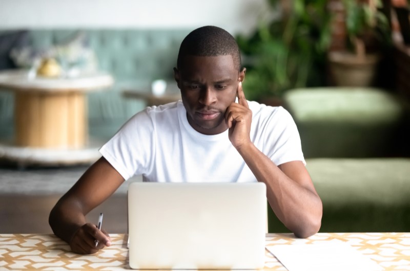 Qual a diferença entre consórcio e financiamento | Foto de um homem concentrado na frente do notebook | Dúvidas sobre dívidas | Eu Dou Conta