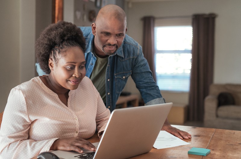 8 dicas para economizar energia no verão | Foto de um casal concentrado, olhando para um notebook | Economia e renda extra | Eu Dou Conta 