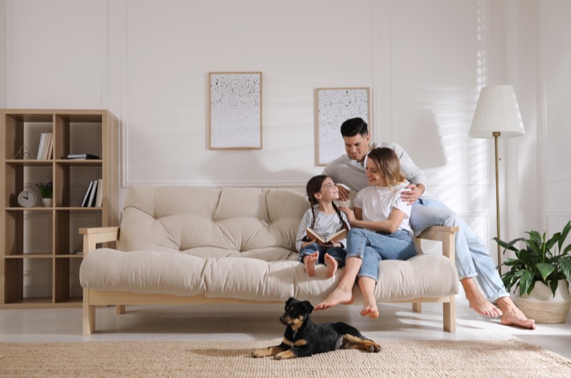 Bairros da Zona Norte de São Paulo | Foto de uma família feliz na sala, junto com um cachorro de estimação | Trilha da Conquista | Blog da Tenda 