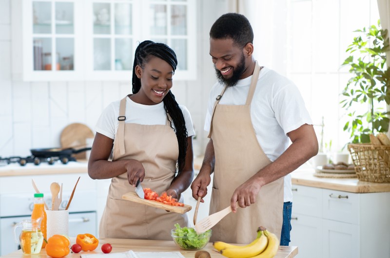 Higienize e conserve os alimentos corretamente | Foto de um casal sorridente preparando um refeição na cozinha | Economia e renda extra | Eu Dou Conta 