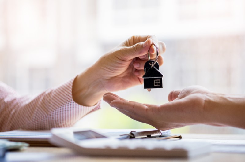 Desmistifique o valor para dar de entrada em um apartamento | Foto de uma pessoa entregando um chaveiro de casinha para outra pessoa | Economia e renda extra | Eu Dou Conta 