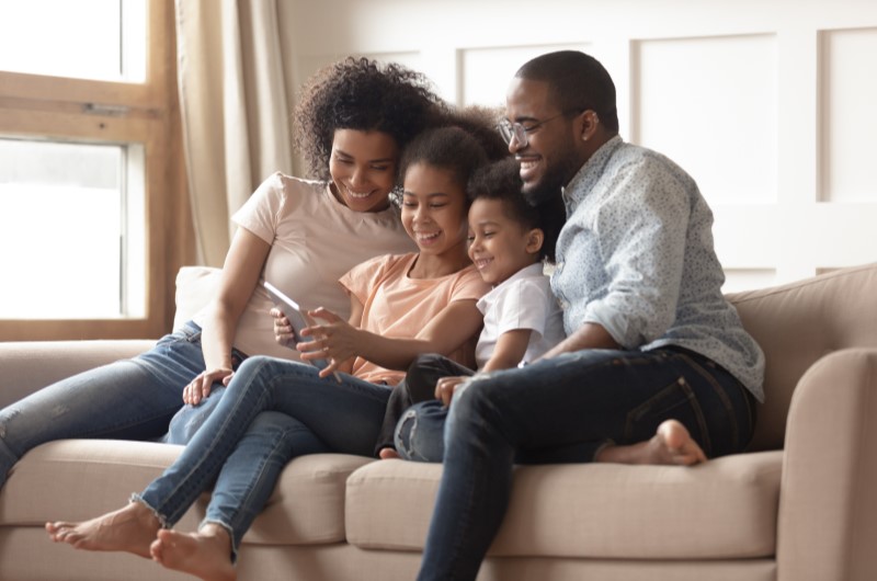 Engenho Novo | Foto de uma família feliz sentada no sofá da sala | Trilha da Conquista | Blog da Tenda