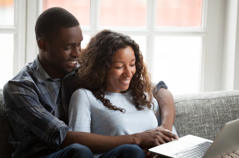 Fantasias de Carnaval para casal | Foto de um casal sentado no sofá usando o notebook | Economia e Renda Extra | Eu Dou Conta 