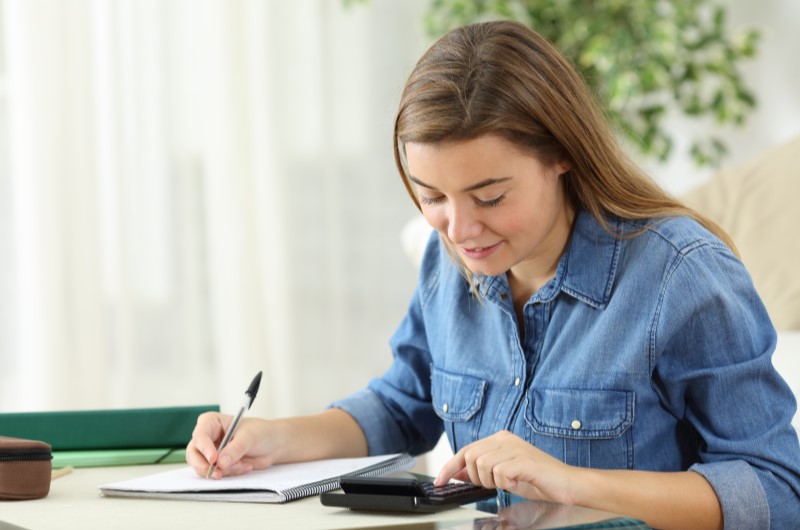 Qual o valor para dar entrada em um apartamento? | Foto de uma mulher fazendo contas com uma calculadora | Economia e renda extra | Eu Dou Conta 