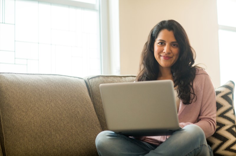 Valorização do imóvel | Foto de uma moça sentada no sofá com um notebook | Economia e renda extra | Eu Dou Conta 