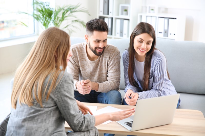 Apartamento da Construtora Tenda no bairro Taquara | Foto de um casal conversando com uma corretora de imóveis e oolhando para o notebook | Trilha da Conquista | Blog da Tenda