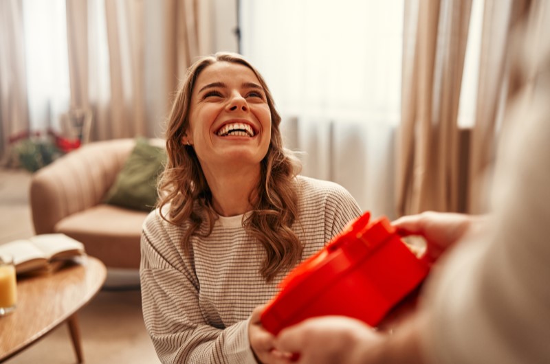 Caixa de mimos | Foto de uma moça sorridente recebendo uma caixinha vermelha | Economia e renda extra | Eu Dou Conta 