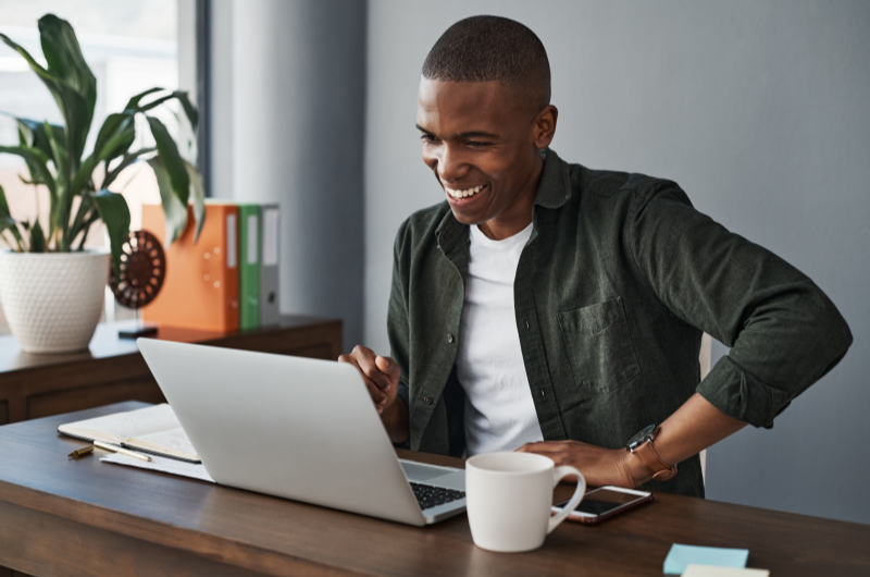 Como é morar no bairro Taquara | Foto de um homem sorridente utilizando o notebook | Trilha da Conquista | Blog da Tenda