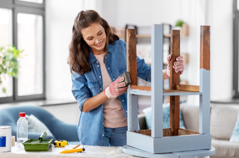 Ideias de decoração faça você mesmo | Foto de uma moça reformando um banquinho de madeira na cor azul | Casa e Decoração | Blog da Tenda