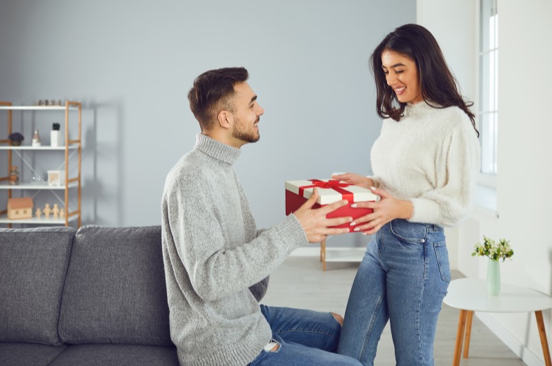 Presentes para o Dia dos Namorados: 10 ideias baratas e criativas | Foto de um casal de namorados entregando um presente com um laço vermelho | Economia e renda extra | Eu Dou Conta 