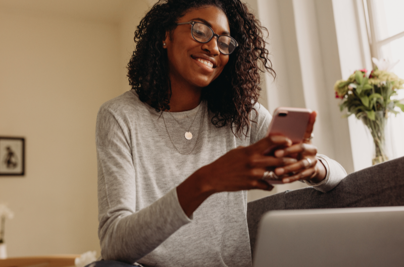 Espaço das Américas | Foto de uma moça sorridente usando o celular | Trilha da Conquista | Blog da Tenda