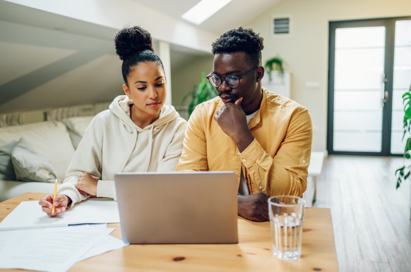 Quais são alguns exemplos de despesas de casa recorrentes? | Foto de um casal fazendo a contas na frente do notebook | Economia e renda extra | Eu Dou Conta 