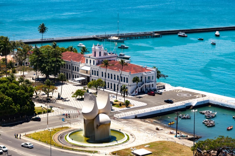 Como é morar em Salvador? | Foto aérea da cidade de Salvador, mostrando a cidade e um mar azul intenso | Trilha da Conquista | Blog da Tenda