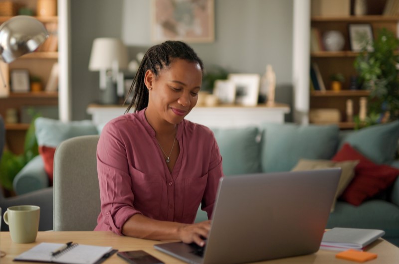 Conheça a reputação da construtora | Mulher usando o notebook na sala de estar | Casa e decoração | Blog da Tenda