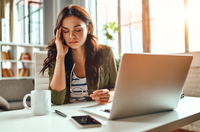 Erros que prejudicam sua saúde financeira | Mulher com expressão cansada na frente do notebook | Como limpar o seu nome | Eu Dou Conta 