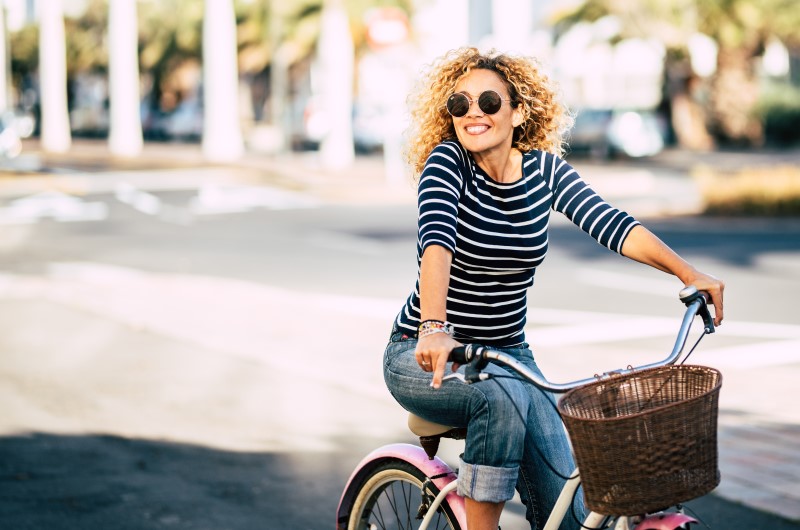 Vantegens de morar em Salvador | Foto de uma mulher sorridente andando de bicicleta | Trilha da Conquista | Blog da Tenda