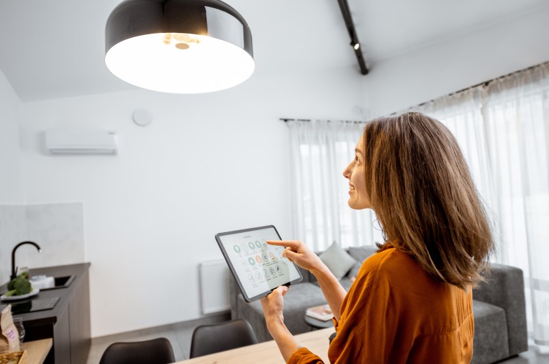 Iluminação e uso da energia | Mulher controlando a iluminação de casa com um controle | Casa e Decoração | Blog da Tenda