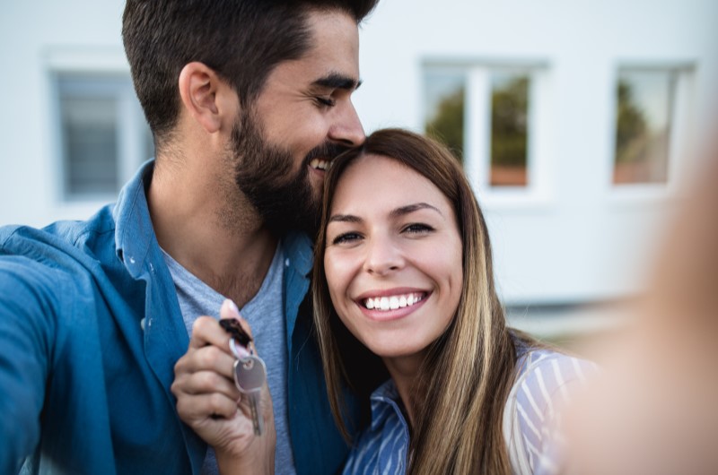 Um casal sorridente segurando as chaves do apartamento novo | Dicas para fazer uma boa compra de apartamento | Trilha da Conquista | Blog da Tenda