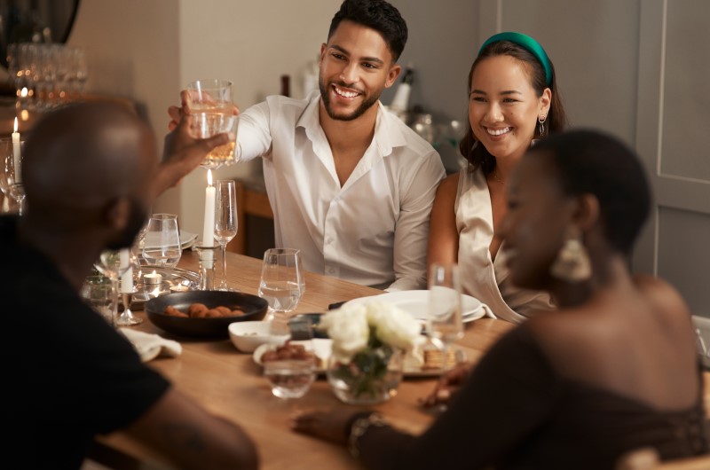 O que é chá de casa nova? | Amigos sorridentes comemorando em uma mesa de jantar | Casa e Decoração | Blog da Tenda