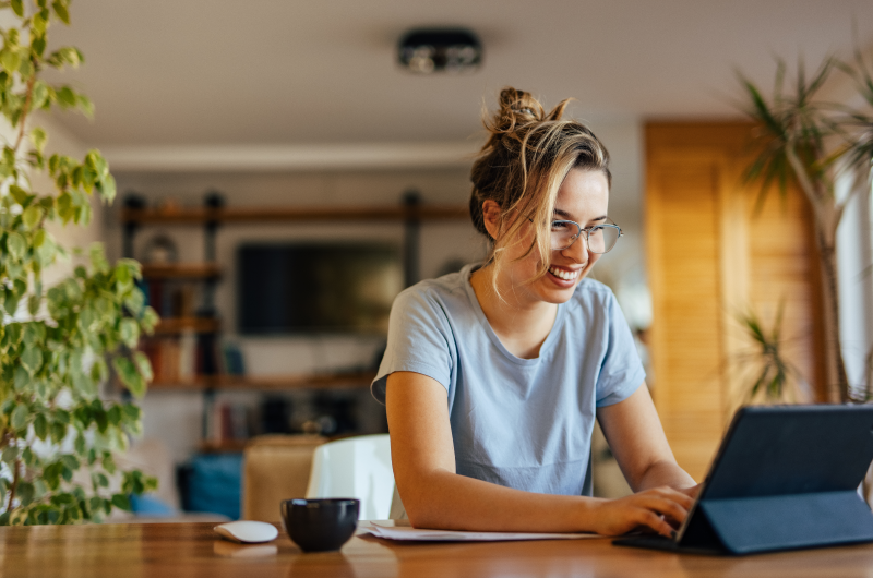 Regras de boa convivência em condomínio: o que você deve saber | Mulher sorridente usando o notebook | Viver em Condomínio | Blog da Tenda 