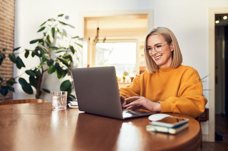 Cadeiras dobráveis | Mulher sorridente usando o notebook em casa | Casa e Decoração | Blog da Tenda