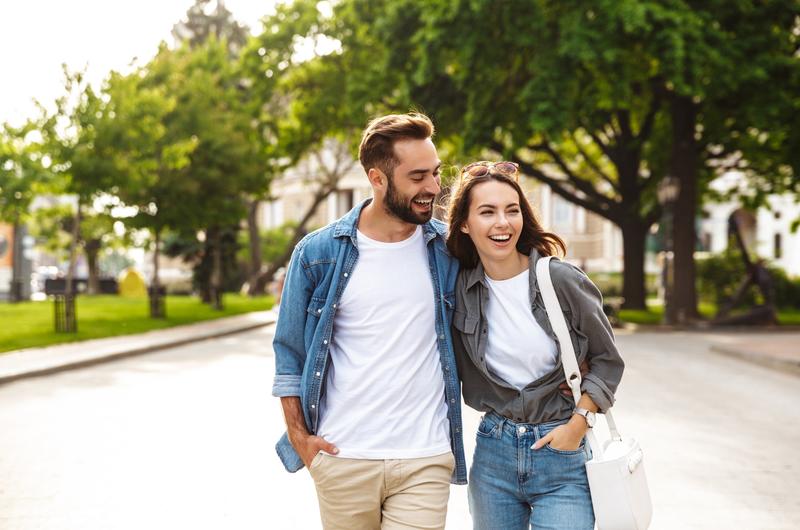 Quais são os bairros da Zona Norte de Recife | Casal sorridente caminhando em uma praça | Trilha da Conquista | Blog da Tenda 