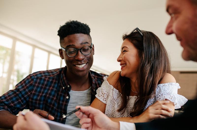 Composição de renda | Casal sorridente conversando com um corretor de imóvel | Blog da Tenda 