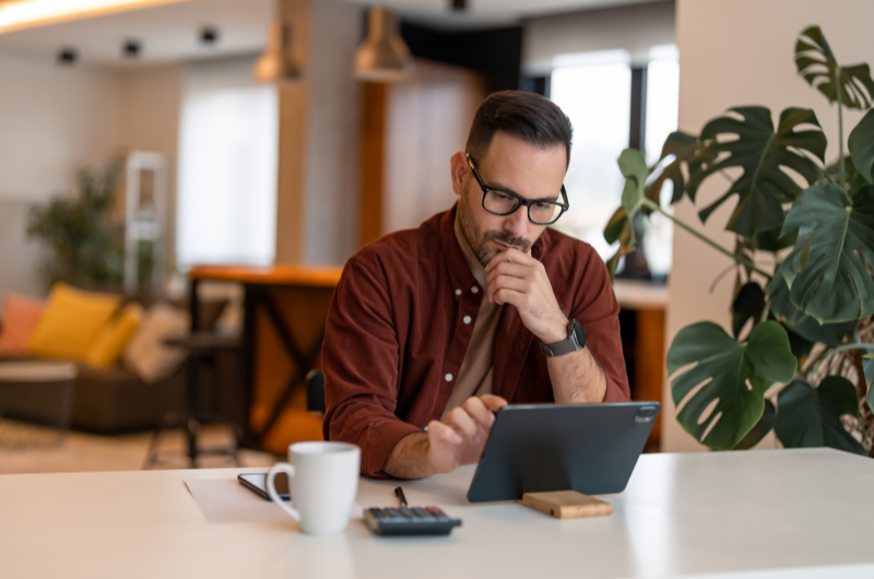 Faça uma Simulação de Financiamento | Homem concentrado usando um tablet em uma mesa de escritório moderno | Minha Casa Minha Vida | Blog da Tenda 