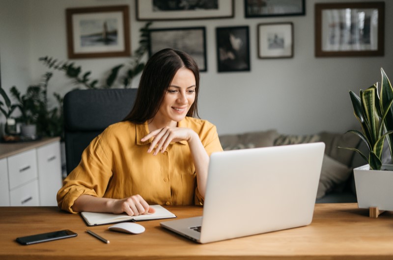 Qualidade de vida | Mulher sorrindo enquanto trabalha no notebook | Eu Dou Conta | Blog da Tenda 