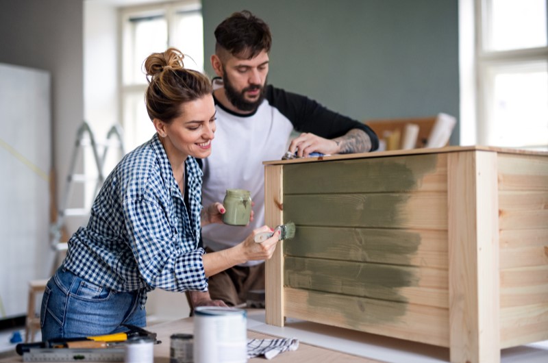 Reaproveite móveis antigos | Casal pintando juntos um móvel de madeira, em ambiente descontraído e criativo | Casa e Decoração | Blog da Tenda