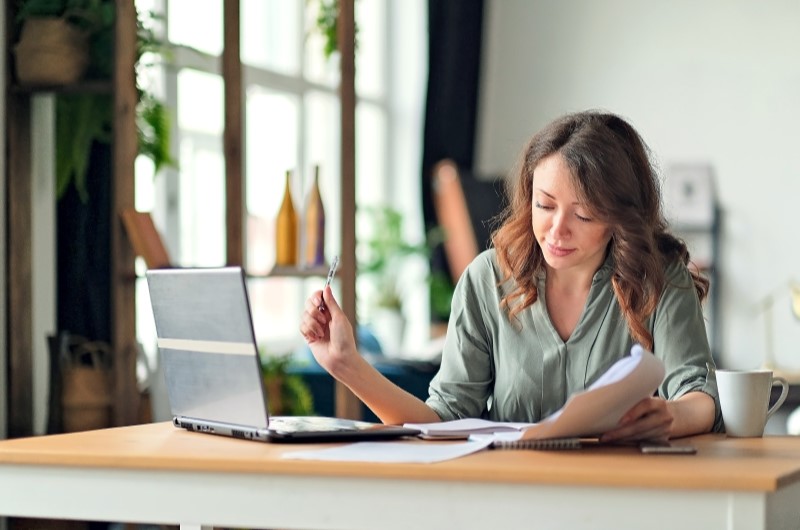 Situações que o FGTS não pode ser usado | Mulher trabalhando com laptop e documentos em uma mesa | Trilha da Conquista | Blog da Tenda 