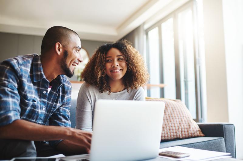 Valorização do imóvel | Casal revisando documentos juntos, usando um notebook em um ambiente acolhedor | Viver em Condomínio | Blog da Tenda
