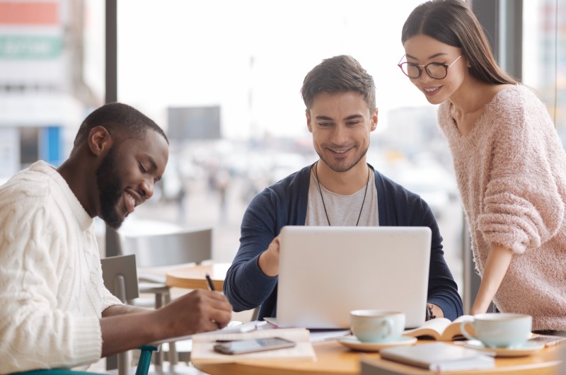 Do estágio à liderança | Três colegas trabalhando juntos em um notebook, com anotações e xícaras na mesa | Jeito Tenda de Ser | Blog da Tenda 